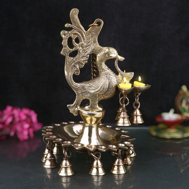 A stunning Brass Peacock Diya Hanging with Bells, featuring a graceful peacock design with a shiny brass finish.  India’s Largest Pooja Accessories Brand – www.satvikstore.in